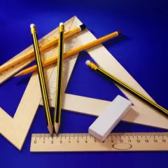 Przyrządy geometryczne i ołówki na niebieskim tle. Pomagają mierzyć i rysować, jak liczby rzeczywiste na osi.