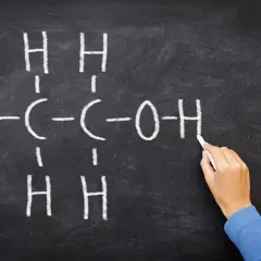 Rysunek na tablicy przedstawia wzór etanolu, kluczowego związku w chemii alkoholi.