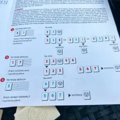 Zasady gry Rummikub: przykłady ułożeń serii i wymiany jokera na stole i na tabliczce gracza.