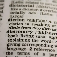Słownik wyjaśnia słowo "dictionary" jako książkę z alfabetycznym spisem słów i ich znaczeń.