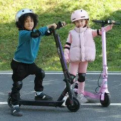 Dzieci w kaskach i ochraniaczach gotowe do jazdy na elektrycznych hulajnogach. Od ilu lat można jeździć na hulajnodze elektrycznej? To zależy od przepisów, ale te maluchy wyglądają na gotowe do zabawy!