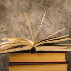 Otwarta księga na stosie innych. Czy wiedza pomoże nam zawieźć marzenia, czy może zawieść w drodze do celu?
