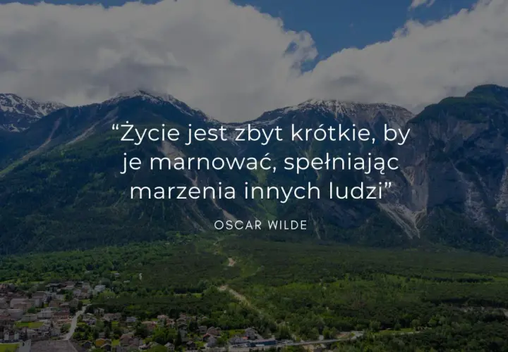 Mądre cytaty krótkie: "Życie jest zbyt krótkie, by je marnować, spełniając marzenia innych ludzi" - Oscar Wilde. Góry i miasteczko w tle.