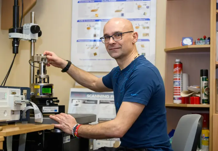 Naukowcowiec pracuje przy zaawansowanym sprzęcie, który umożliwia badania w skali nanotechnologii.