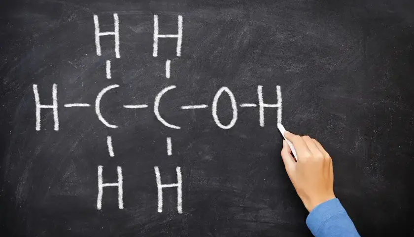 Rysunek na tablicy przedstawia wzór etanolu, kluczowego związku w chemii alkoholi.