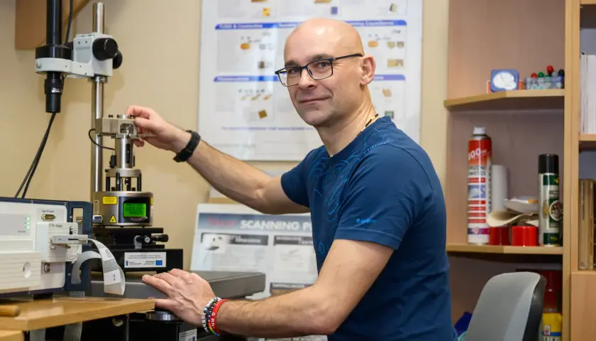 Naukowcowiec pracuje przy zaawansowanym sprzęcie, który umożliwia badania w skali nanotechnologii.