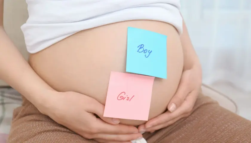 Brzuszek ciężarnej z karteczkami "Boy" i "Girl". Czekamy na decyzję, kto do nas dołączy.
