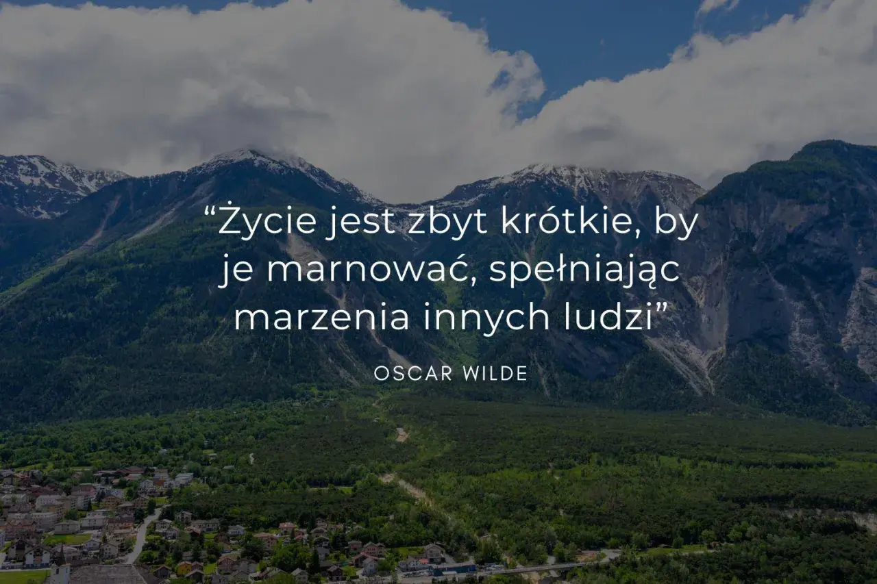 Mądre cytaty krótkie: "Życie jest zbyt krótkie, by je marnować, spełniając marzenia innych ludzi" - Oscar Wilde. Góry i miasteczko w tle.