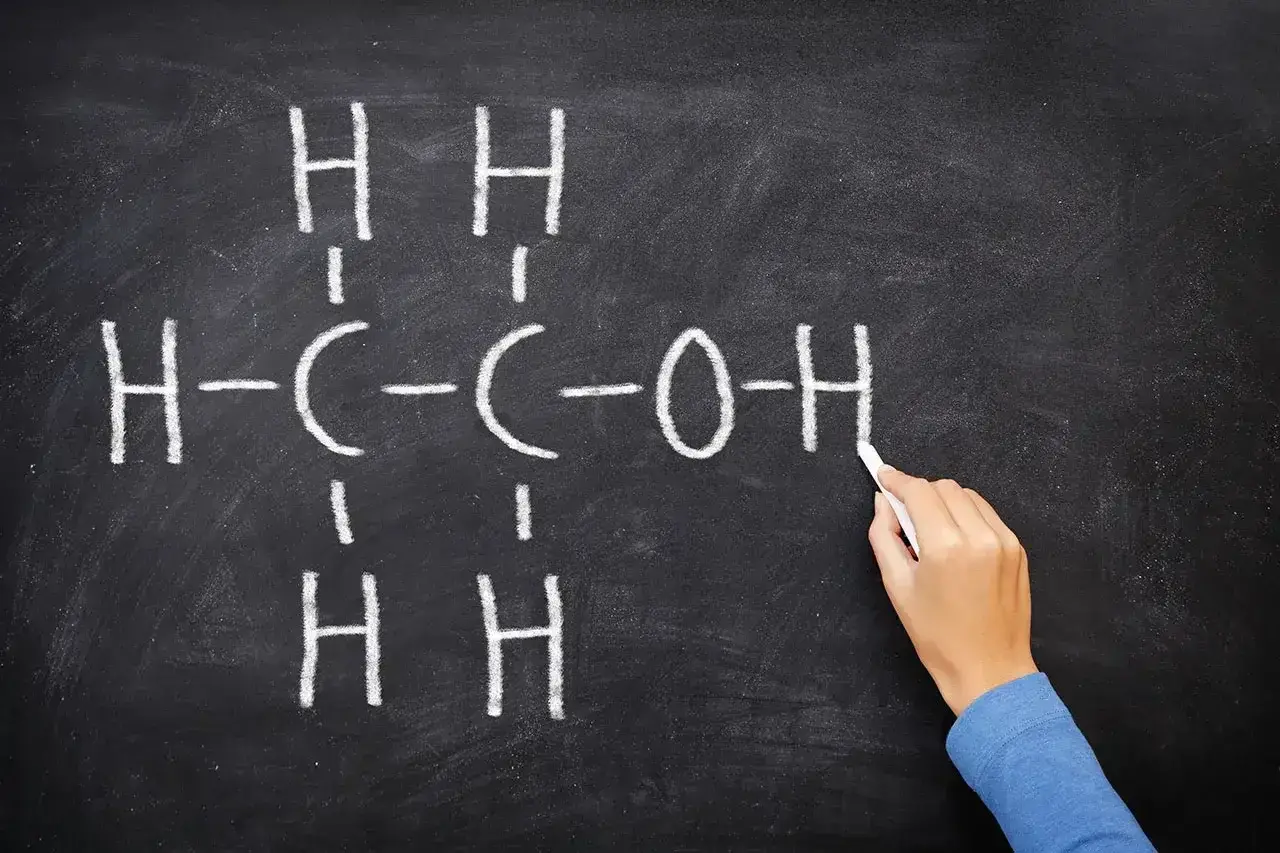 Rysunek na tablicy przedstawia wzór etanolu, kluczowego związku w chemii alkoholi.