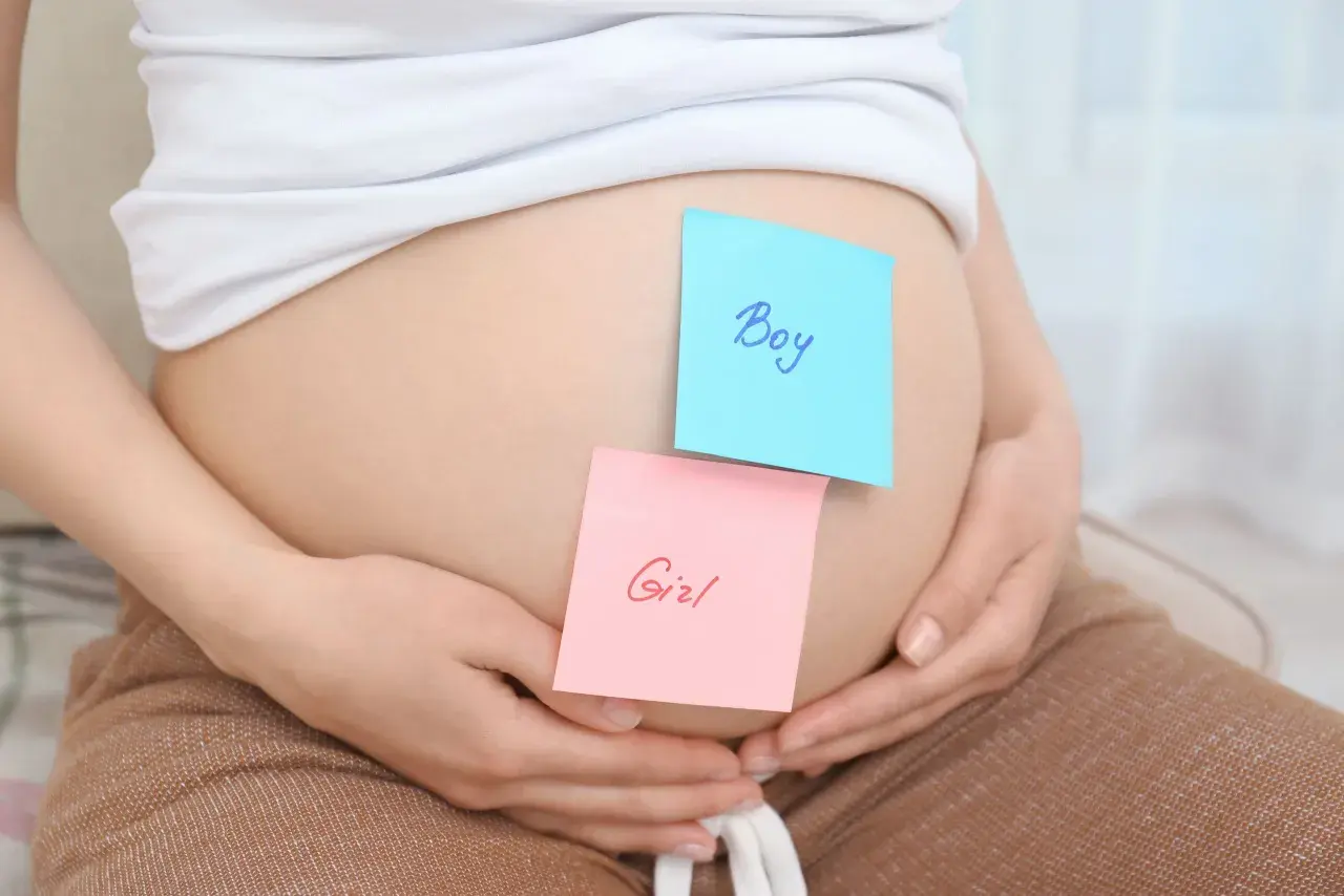 Brzuszek ciężarnej z karteczkami "Boy" i "Girl". Czekamy na decyzję, kto do nas dołączy.