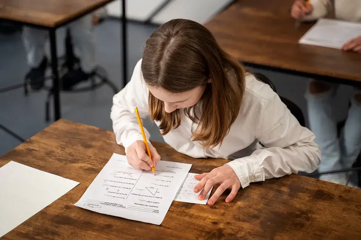 Dziewczynka pisze sprawdzian z matematyki. Szukasz materiałów, gdzie znaleźć sprawdziany z Nowej Ery?